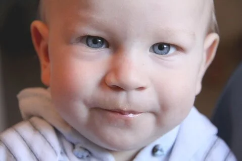 Bild eines kleinen Jungen der in die Kamera blickt.